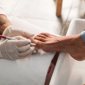 Pedicure session showing gloved hands performing nail care on foot.